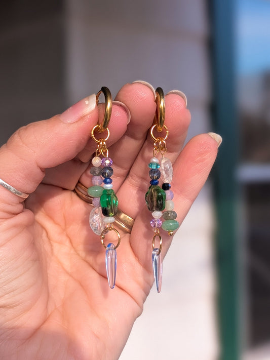 Hand holding two beaded earrings with a blurred background